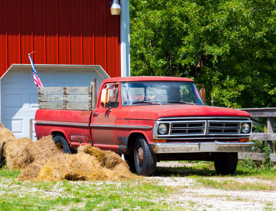 Old red pickup truck in front of a red barn